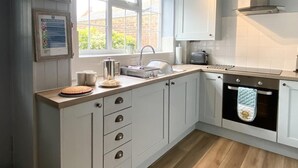 A kitchen with white cabinets, a wooden countertop, a sink, a toaster, and an oven. - 2 Bed in Whitby (oc-w985) (Whitby)