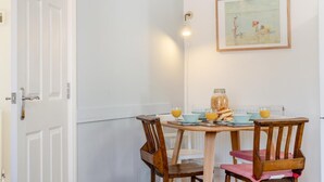 En matplats med ett bord dukat för två personer, en inramad tavla på väggen och en dörr till vänster.