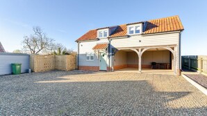 Ein zweistöckiges Haus mit Garage, Schotterweg und Holzzaun.