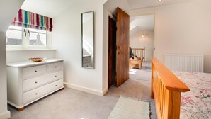 Ein Schlafzimmer mit einem Bett, einem Schminktisch, einem Spiegel und einem Fenster mit einem Streifenrollo.