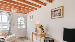Una stanza accogliente con un divano, un piccolo tavolo con una lampada, una TV e un soffitto in legno.
