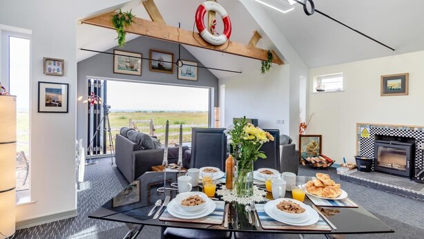 Un coin repas avec une table mise pour le petit-déjeuner, une cheminée et une vue sur l’extérieur.