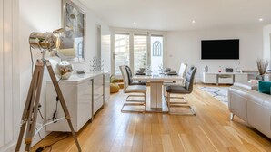 En moderne stue med spiseområde, et ophængt tv og et stativ.