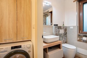 Un baño pequeño con lavadora, lavamanos y retrete.