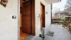 Ein Gebäudeeingang mit Holztüren, einem Metallgitter und einer gefliesten Veranda.