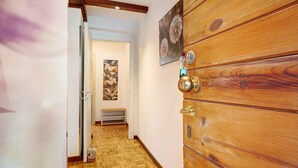 Eine Holztür mit Messingklinke, ein Holzboden und ein Gemälde an der Wand.