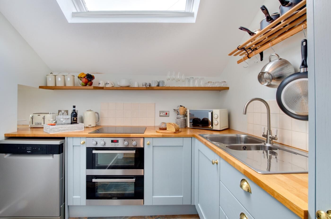 A compact kitchen with a skylight, built-in oven, and a sink.