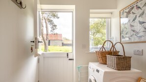 Ein Waschraum mit Waschmaschine, Trockner, einem Fenster mit Aussicht und einem wandmontierten Wäschekorb.