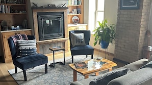 A cozy living room with a fireplace, a bookshelf, a flat-screen TV, and comfortable seating.