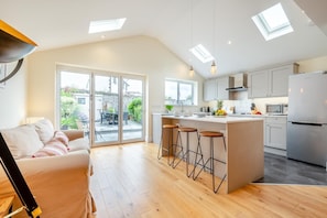 A modern kitchen with a central island, bar stools, and a refrigerator. - 3 Bed in Padstow (oc-s32431) (Padstow)