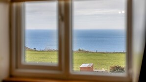 On peut voir, depuis la fenêtre, un champ verdoyant et l’océan.