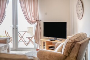 A living room with a television, a sofa, and a sliding glass door leading to an outdoor area. - 4 Bed in Port Mulgrave (oc-wa302) (Port Mulgrave)