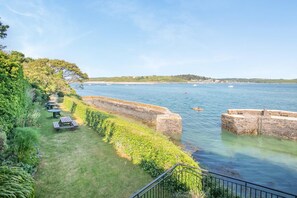 Une zone côtière dotée d’un mur de pierres, de tables de pique-nique et offrant une vue dégagée sur la mer.