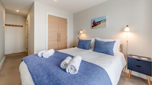 A hotel room with a large bed, two bedside tables, a wardrobe, and a painting on the wall. - 2 Bed in Saunton (oc-10ocea) (Croyde)