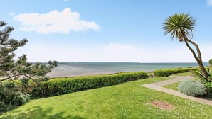 A coastal landscape with a clear sky, a grassy area, a pathway, and a view of the sea. - 2 Bed in Saunton (oc-10ocea) (Croyde)