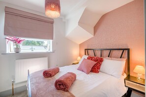 Ein Schlafzimmer mit Bett, Nachttischlampen, einem Fenster mit Blick und einer Heizung.