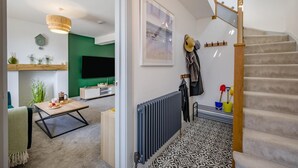 En moderne stue med en grøn accentvæg, et fladskærms-tv og et spiseområde med et sofabord.