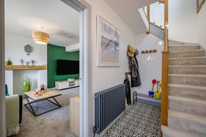 Ein modernes Wohnzimmer mit grüner Akzentwand, einem Flachbildfernseher und einem Essbereich mit Couchtisch.