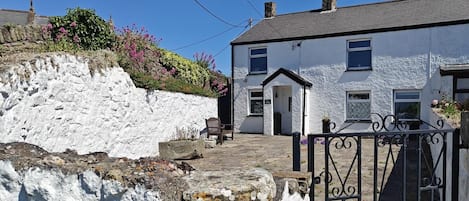 A white building with a stone wall and a gate.