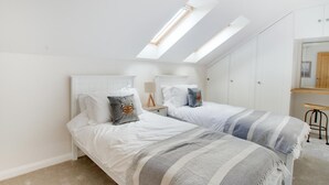A bedroom with two beds, a skylight, a nightstand, a mirror, and a wooden bench. - 2 Bed in Newton (oc-swro) (Newton)