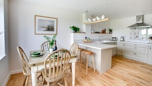A modern kitchen with a central island, wooden chairs, and a dining table set for four. - 2 Bed in Newton (oc-swro) (Newton)