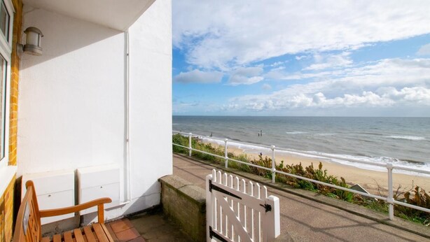 Un balcone con vista sul mare, una ringhiera bianca e una panchina.