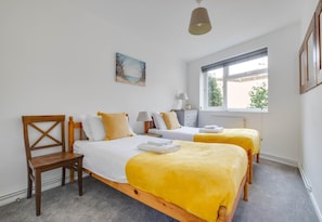 A hotel room with two beds, a wooden chair, a window with a view, and a painting on the wall. - 2 Bed in Southwold (oc-4east) (Southwold)