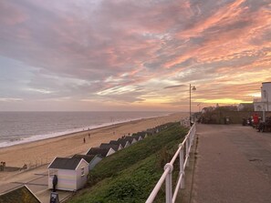 A beach with a row of beach huts and a promenade. - 2 Bed in Southwold (oc-4east) (Southwold)