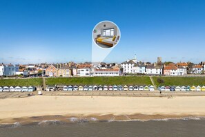 Un pueblo costero con una playa, casas y una hilera de cabañas playeras coloridas.