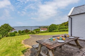 A wooden table set with breakfast items, overlooking a grassy area and a body of water.