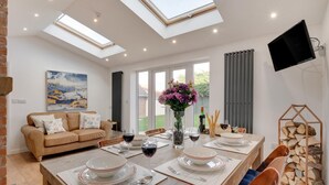 A modern dining area with a high ceiling, skylights, a sofa, and a dining table set for four. - 3 Bed in Whitby (oc-w015) (Whitby)