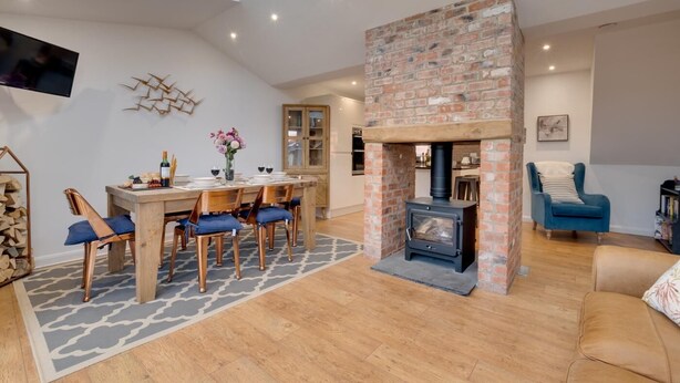 A cozy living room with a fireplace, a dining area with a table and chairs, and a comfortable seating area with a sofa. - 3 Bed in Whitby (oc-w015) (Whitby)