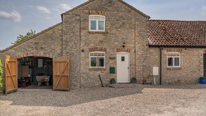 A stone building with a large open door leading to a furnished interior, a white door, and a tiled roof. - 3 Bed in Cawton (oc-t32407) (Cawton)