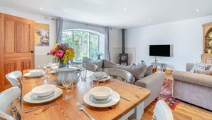 A dining area with a wooden table set for four, a sofa, and a television in a living room. - 3 Bed in Cawton (oc-t32407) (Cawton)