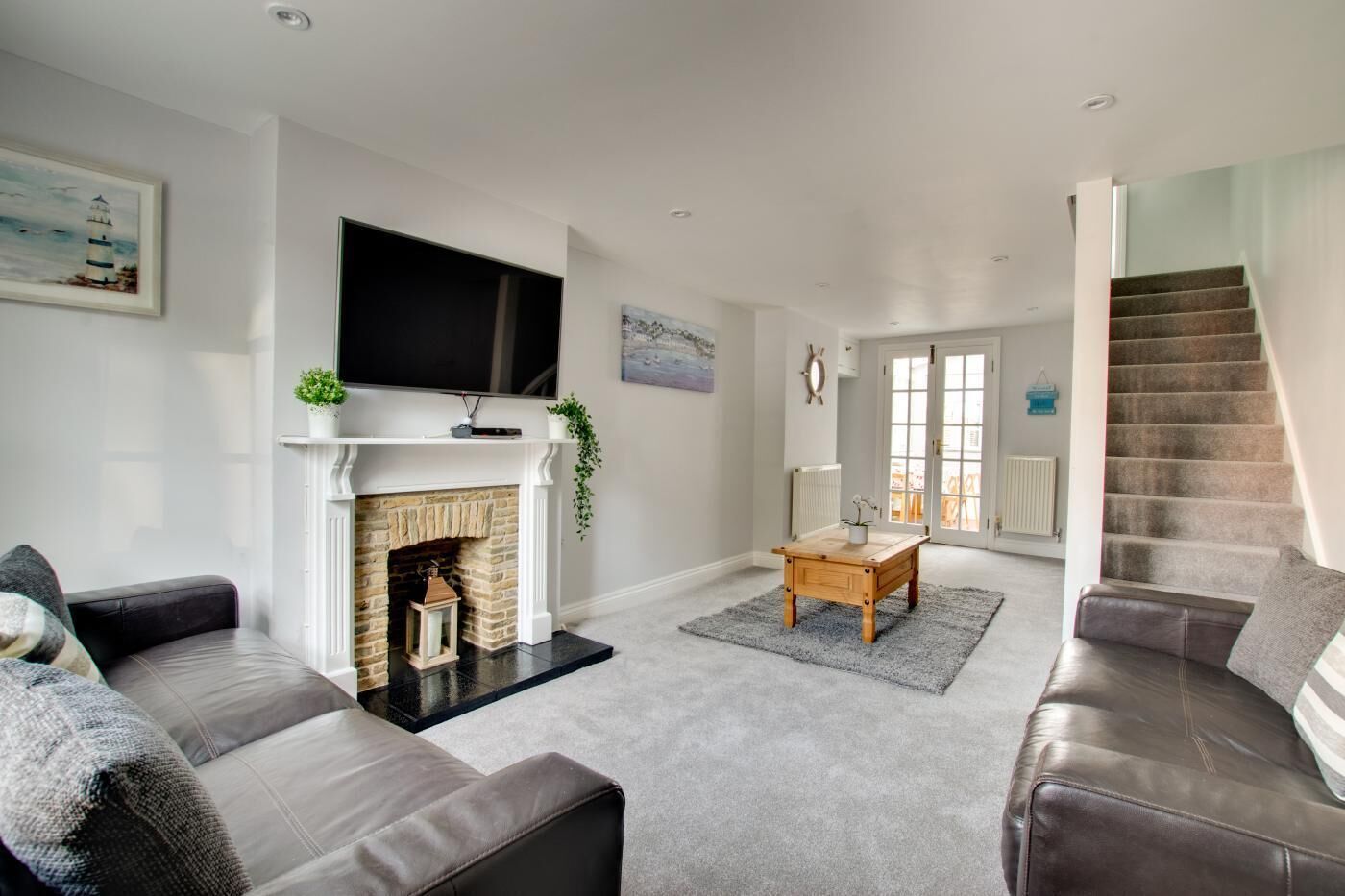 A living room with a fireplace, a television, a sofa, and a staircase.