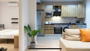 A modern apartment with a kitchenette, a dining area, and a living room with a sofa and a plant. - AR IFEMA modern apartment near airport and trade fair Madrid (Madrid)