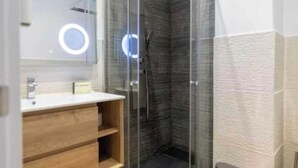 A modern bathroom with a glass-enclosed shower, a wooden vanity, and a large mirror with a circular light. - AR IFEMA modern apartment near airport and trade fair Madrid (Madrid)
