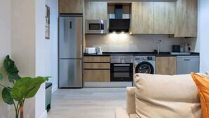 A modern kitchen with wooden cabinets, stainless steel appliances, and a built-in microwave. - AR IFEMA modern apartment near airport and trade fair Madrid (Madrid)