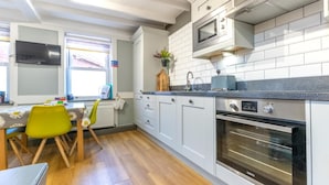 Uma cozinha moderna com armários brancos, micro-ondas, forno e um espaço de refeições com mesa e cadeiras.