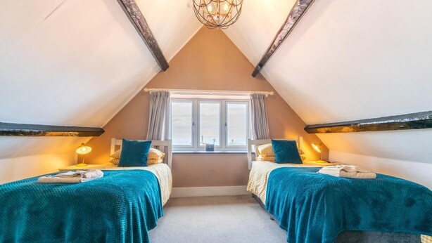 Quarto com duas camas, janela e um candelabro.