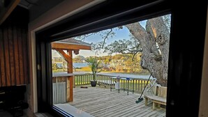 A wooden deck with a view of a lake, a wooden pergola, and a bench.