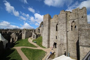A historic stone castle with ruins, a grassy courtyard, and a clear sky. - 3 Bed in Mumbles (oc-hh386) (The Mumbles)
