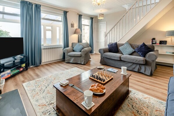 Een woonkamer met een bank, fauteuil, salontafel en een televisie.