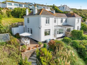 A two-story white house with a conservatory, a patio with outdoor furniture, and a garden with various plants. - 3 Bed in Praa Sands (oc-p00859) (Praa Sands)