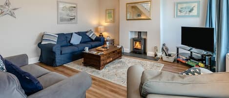 A cozy living room with a sofa, a coffee table, a fireplace, and a television.