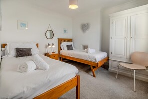 A hotel room with two beds, a chair, a wardrobe, and a window. - 3 Bed in Praa Sands (oc-p00859) (Praa Sands)