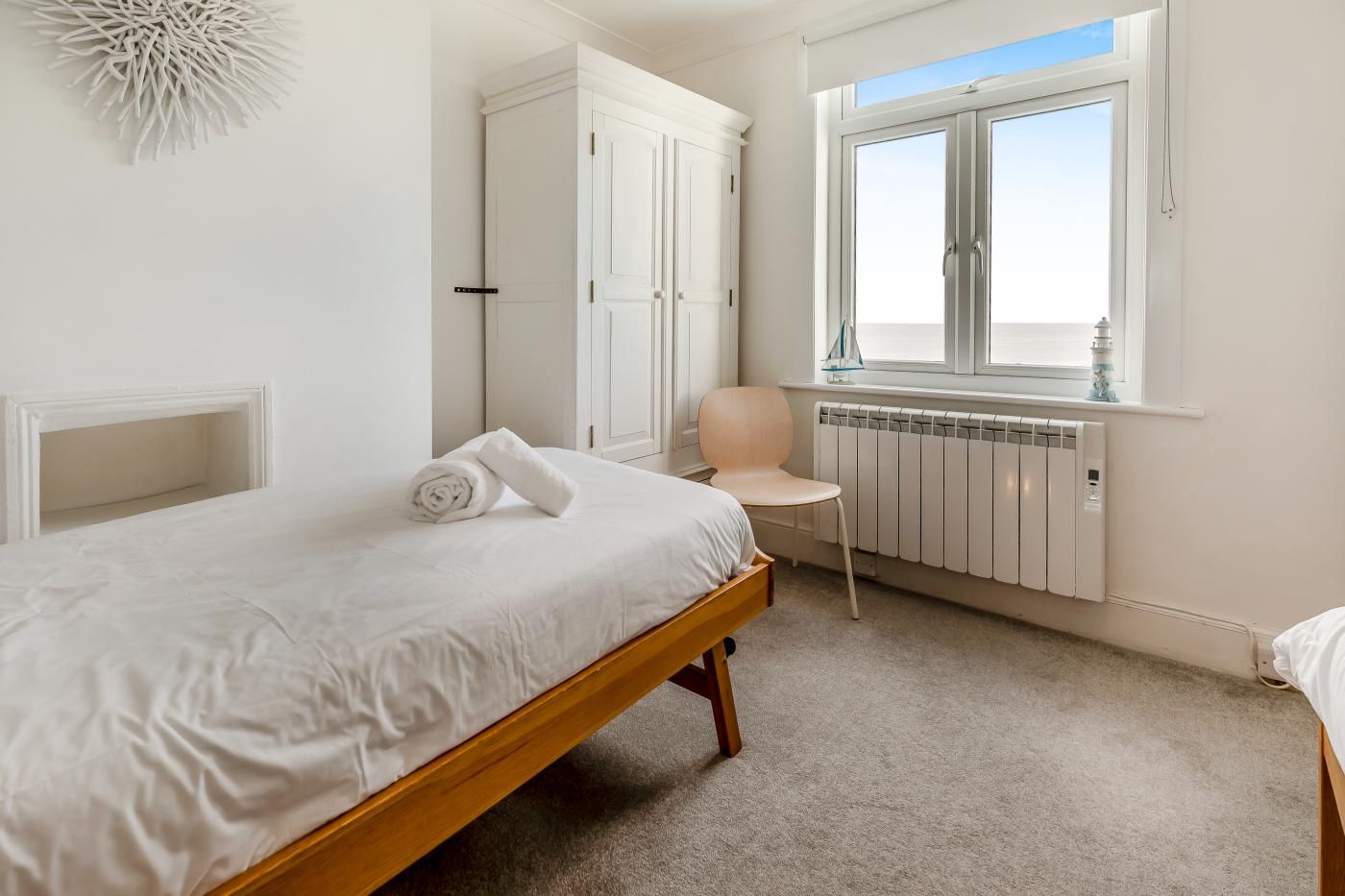 A bedroom with a bed, a chair, a radiator, and a window with a view.