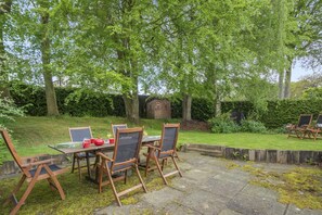 An outdoor dining area with a table and chairs, surrounded by trees and a hedge. - 4 Bed in Ilkley (oc-ds168) (Ilkley)