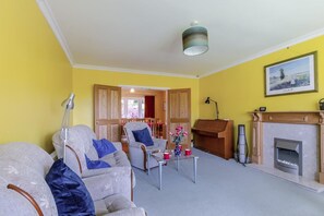 A living room with a fireplace, a dining area, and a hallway leading to another room. - 4 Bed in Ilkley (oc-ds168) (Ilkley)