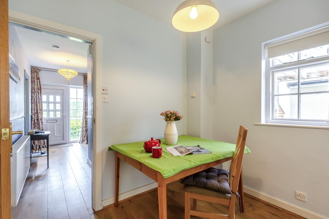 Un coin repas comprenant une table, des chaises, un vase avec des fleurs et une fenêtre donnant sur un paysage.